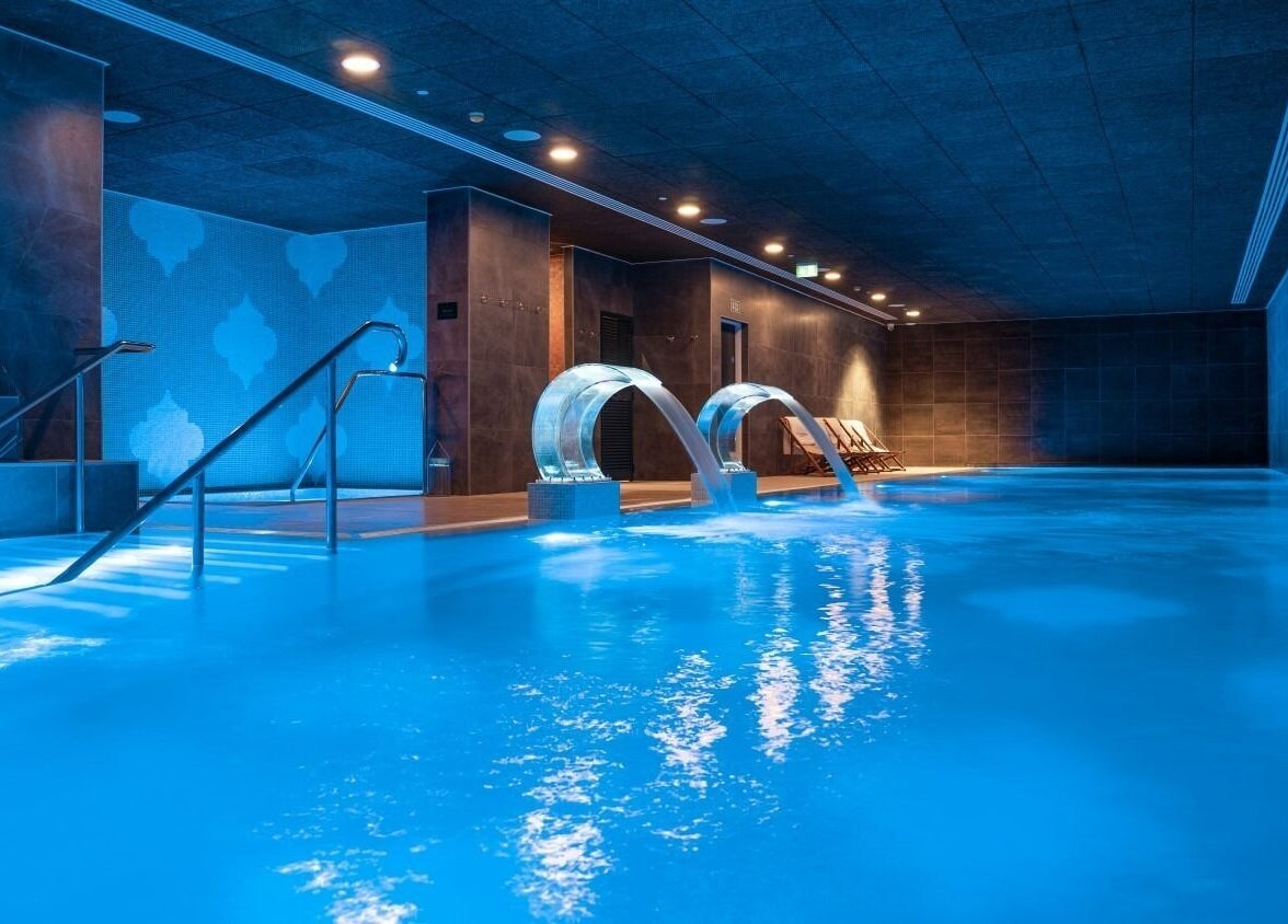 Luxurious indoor pool at E1 Spa and Wellness, Gibraltar, GI with ambient lighting and relaxation areas.