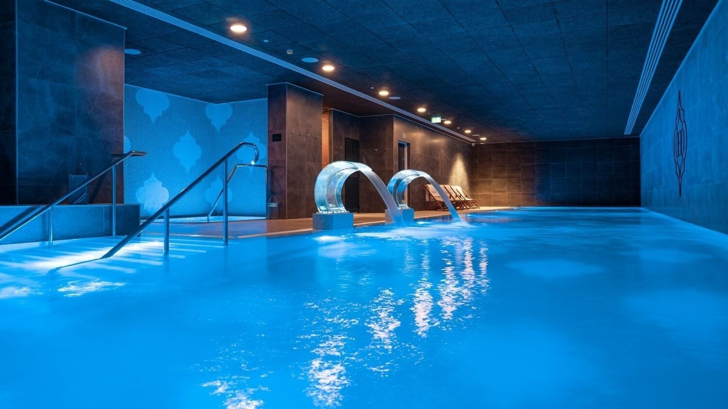 Luxurious indoor pool at E1 Spa and Wellness, Gibraltar, GI with ambient lighting and relaxation areas.