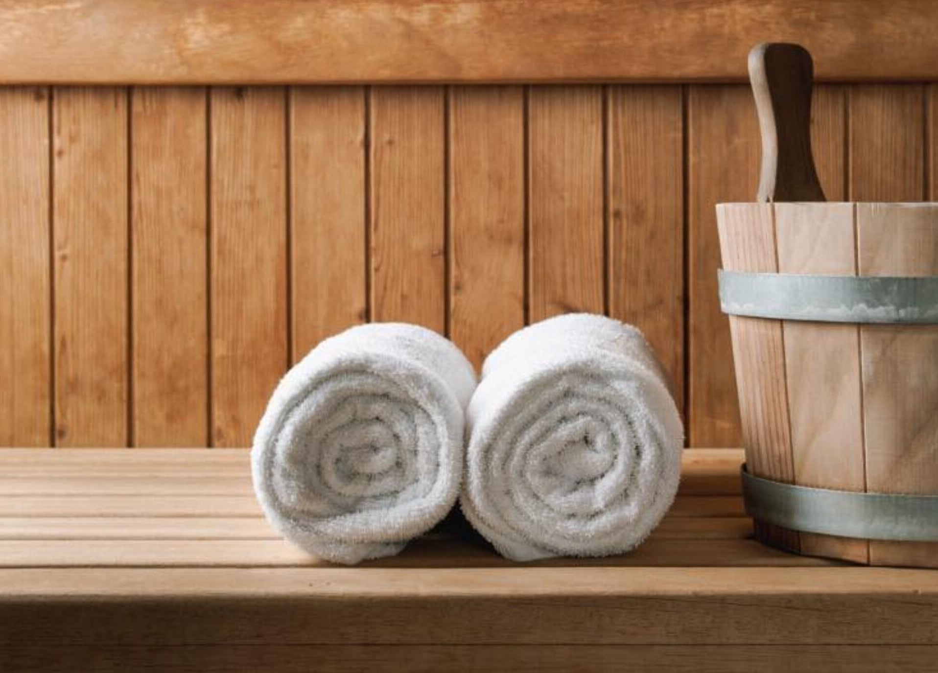 Rolled towels and wooden bucket in E1 Spa and Wellness, Gibraltar, GI, creating a serene spa ambiance.