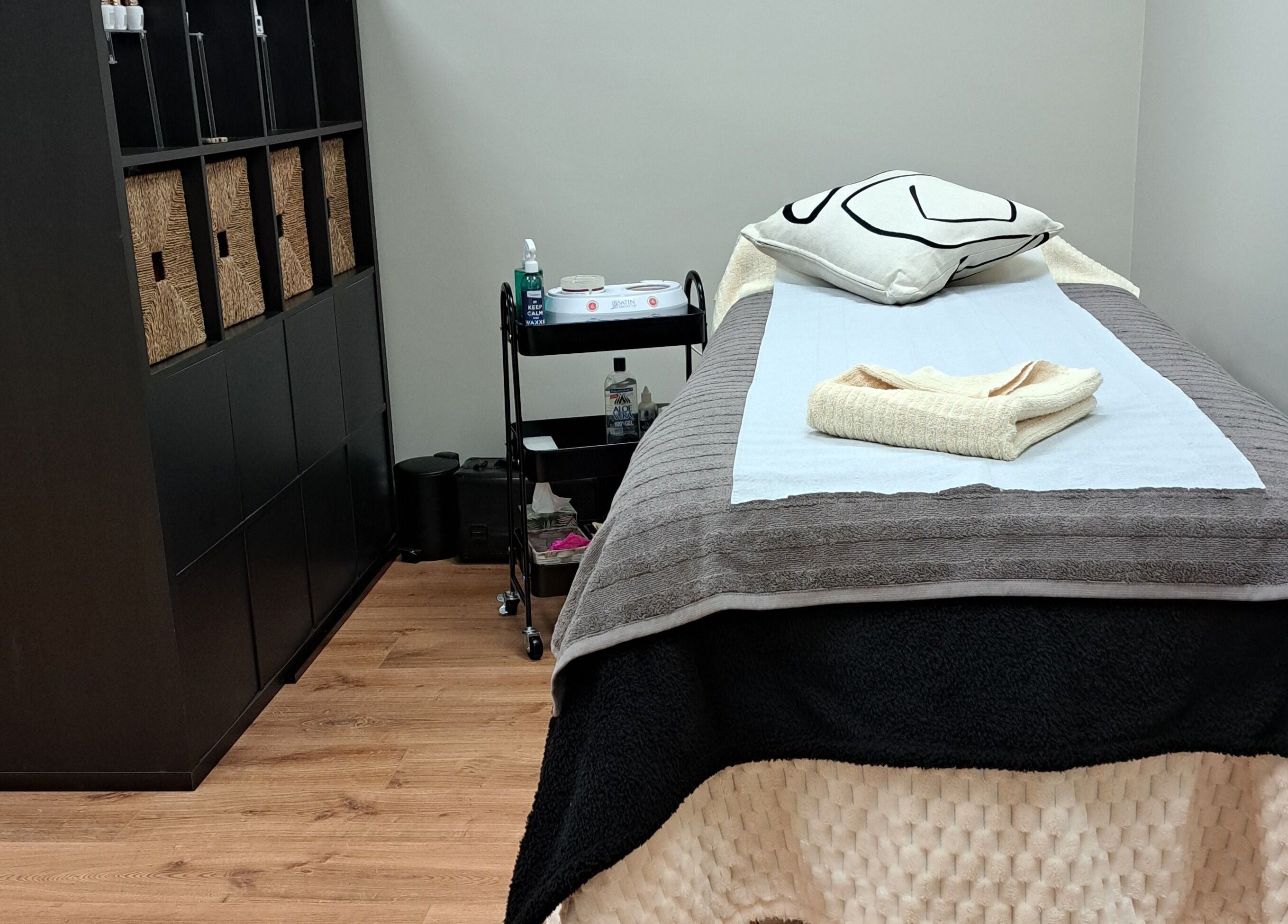JH Specialised Waxing treatment room in Carrickmines, County Dublin, IE, featuring a cozy bed and organized shelves.