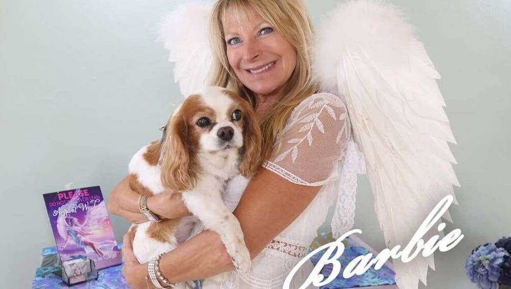 Woman in angel wings holding dog at AngelHairBarbie-SanibelFit4Life, Sanibel, Florida, US.