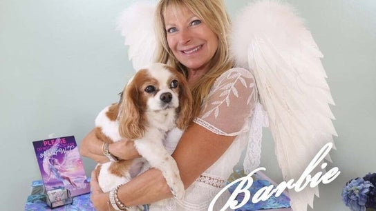 Woman in angel wings holding dog at AngelHairBarbie-SanibelFit4Life, Sanibel, Florida, US.