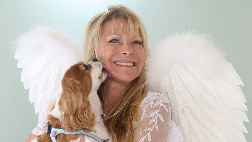Smiling woman with angel wings and dog at AngelHairBarbie-TerraWalkBabcockRanch, Alva, Florida, US.