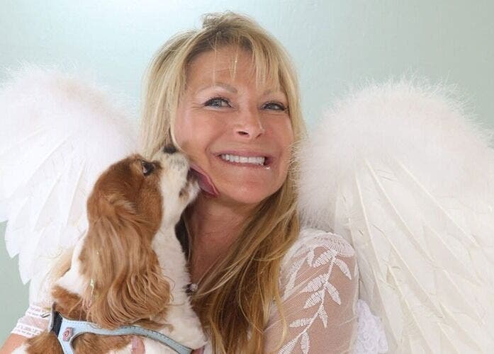 Smiling woman with angel wings and dog at AngelHairBarbie-TerraWalkBabcockRanch, Alva, Florida, US.