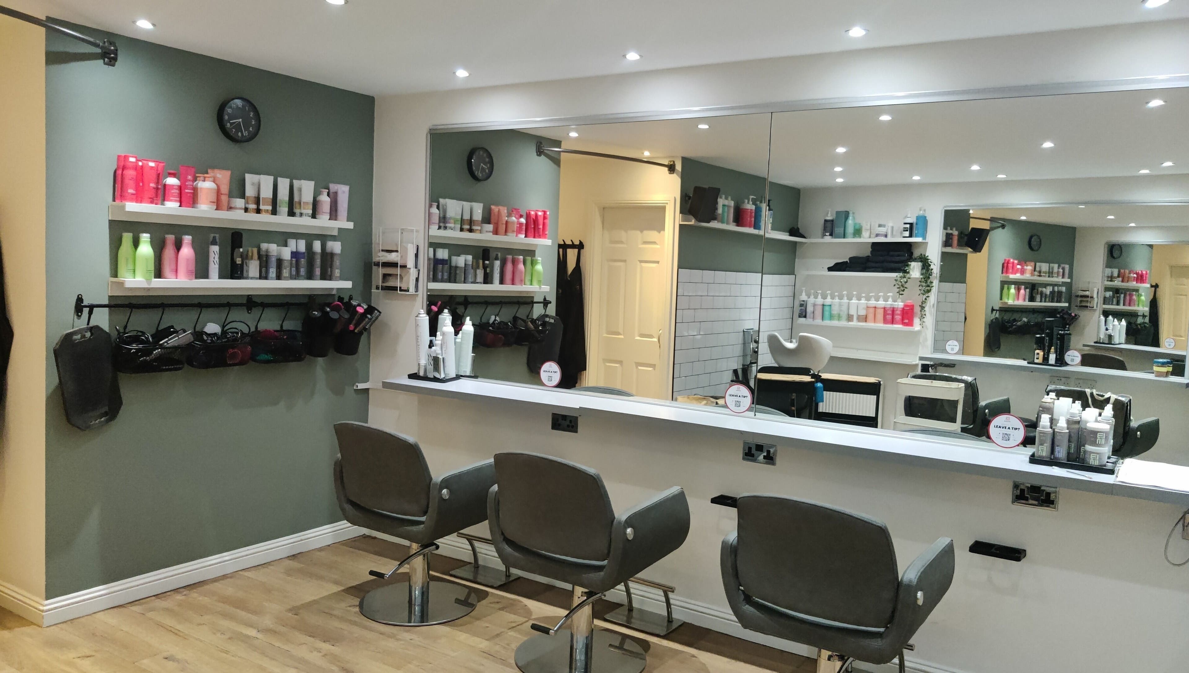 Modern salon interior at Enhance Hair & Beauty, Clarkston, Scotland, GB with stylish chairs and product shelves.