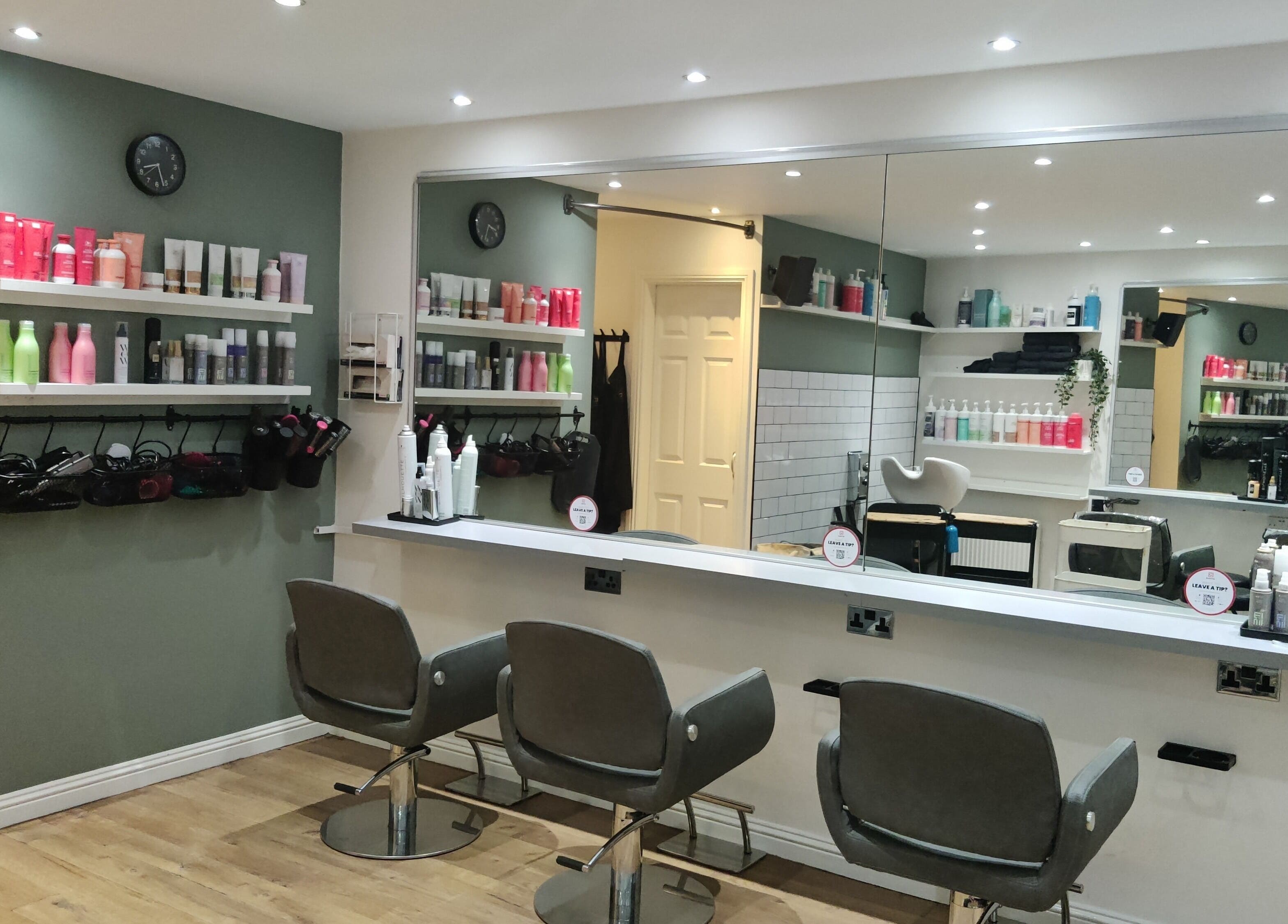 Modern salon interior at Enhance Hair & Beauty, Clarkston, Scotland, GB with stylish chairs and product shelves.