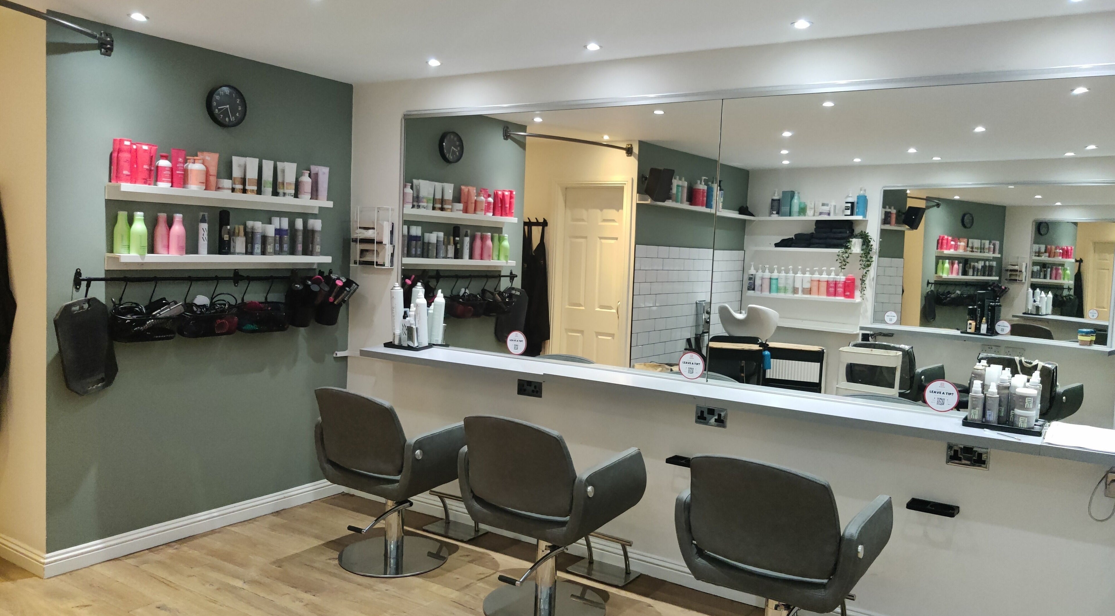 Modern salon interior at Enhance Hair & Beauty, Clarkston, Scotland, GB with stylish chairs and product shelves.