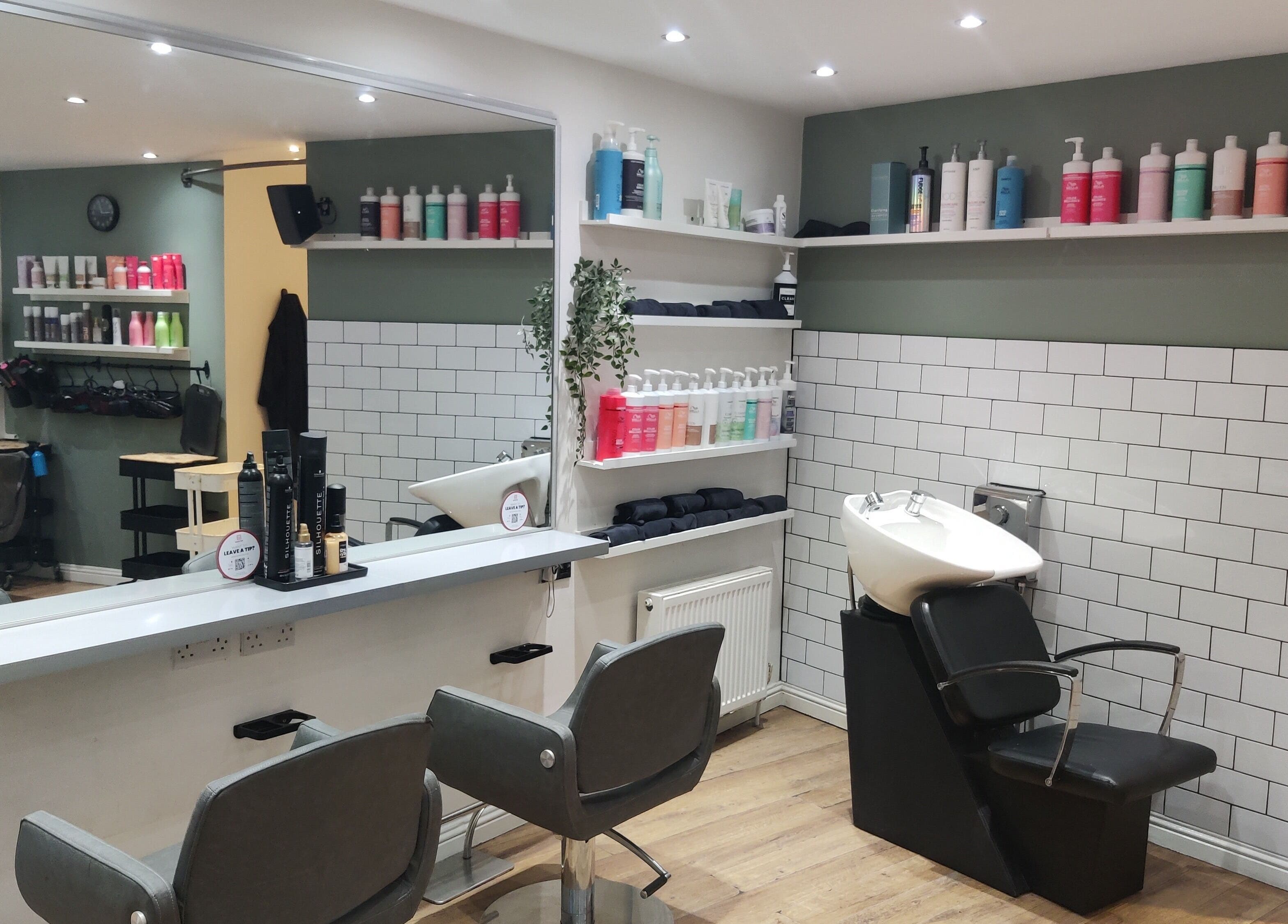 Elegant interior of Enhance Hair & Beauty in Clarkston, Scotland, GB showcasing modern salon chairs and product shelves.