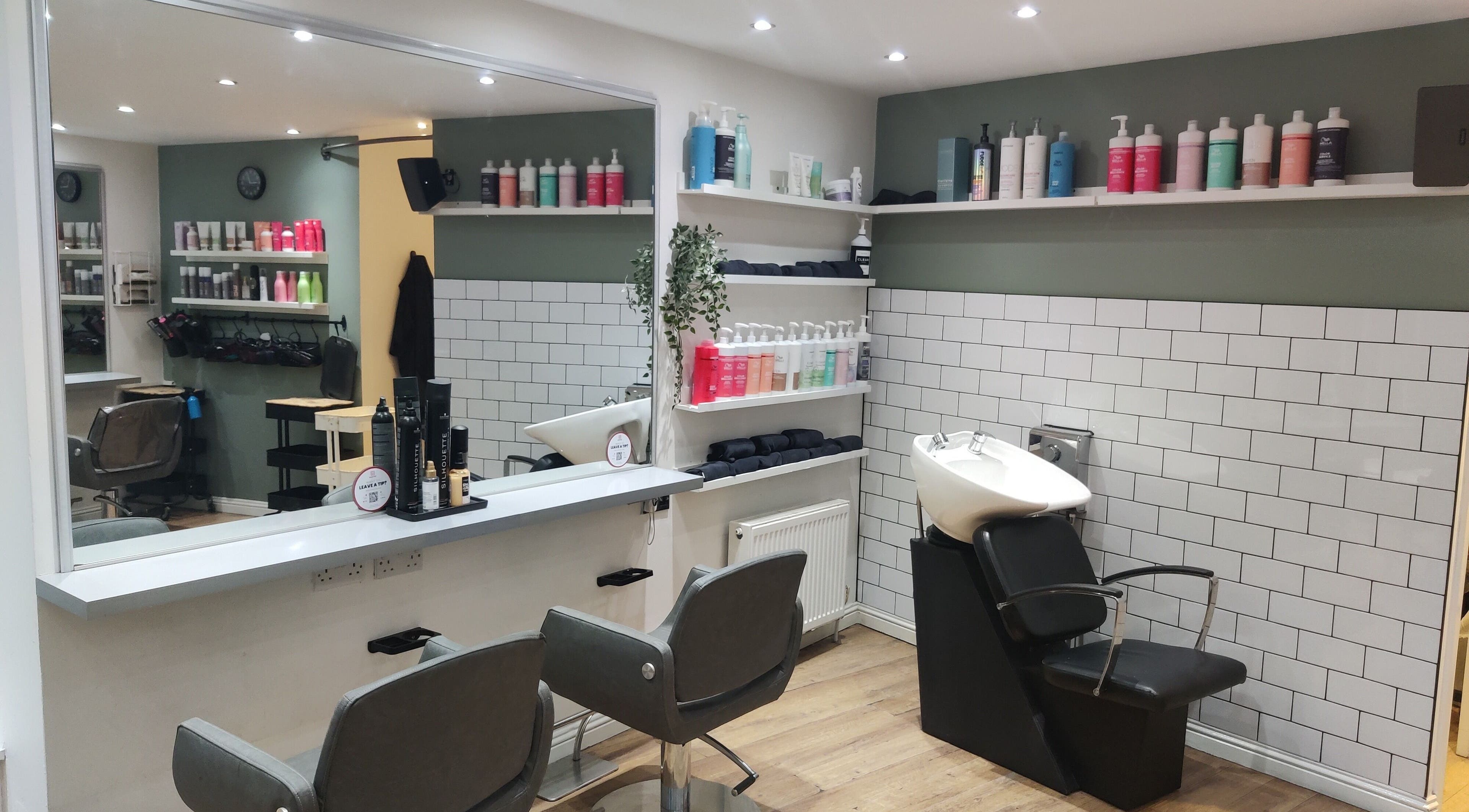 Elegant interior of Enhance Hair & Beauty in Clarkston, Scotland, GB showcasing modern salon chairs and product shelves.