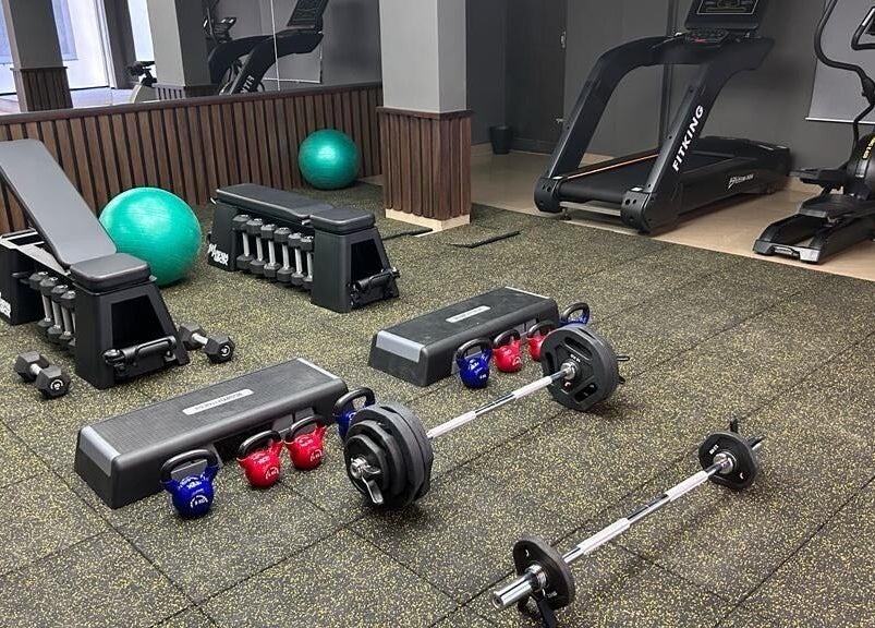 Modern gym setup at One Touch Fit & Glam, Thiruvananthapuram, Kerala, IN. Includes treadmill, weights, and bench.