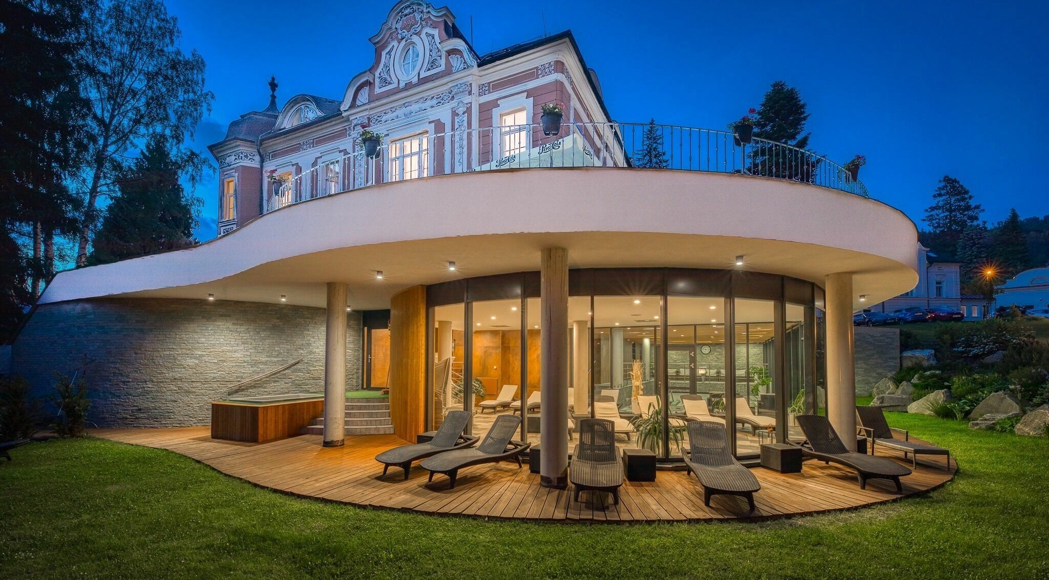 Wellness and Spa Hotel Villa Regenhart v Jeseník, Olomoucký kraj, CZ při večerním osvětlení s relaxačními lehátky.