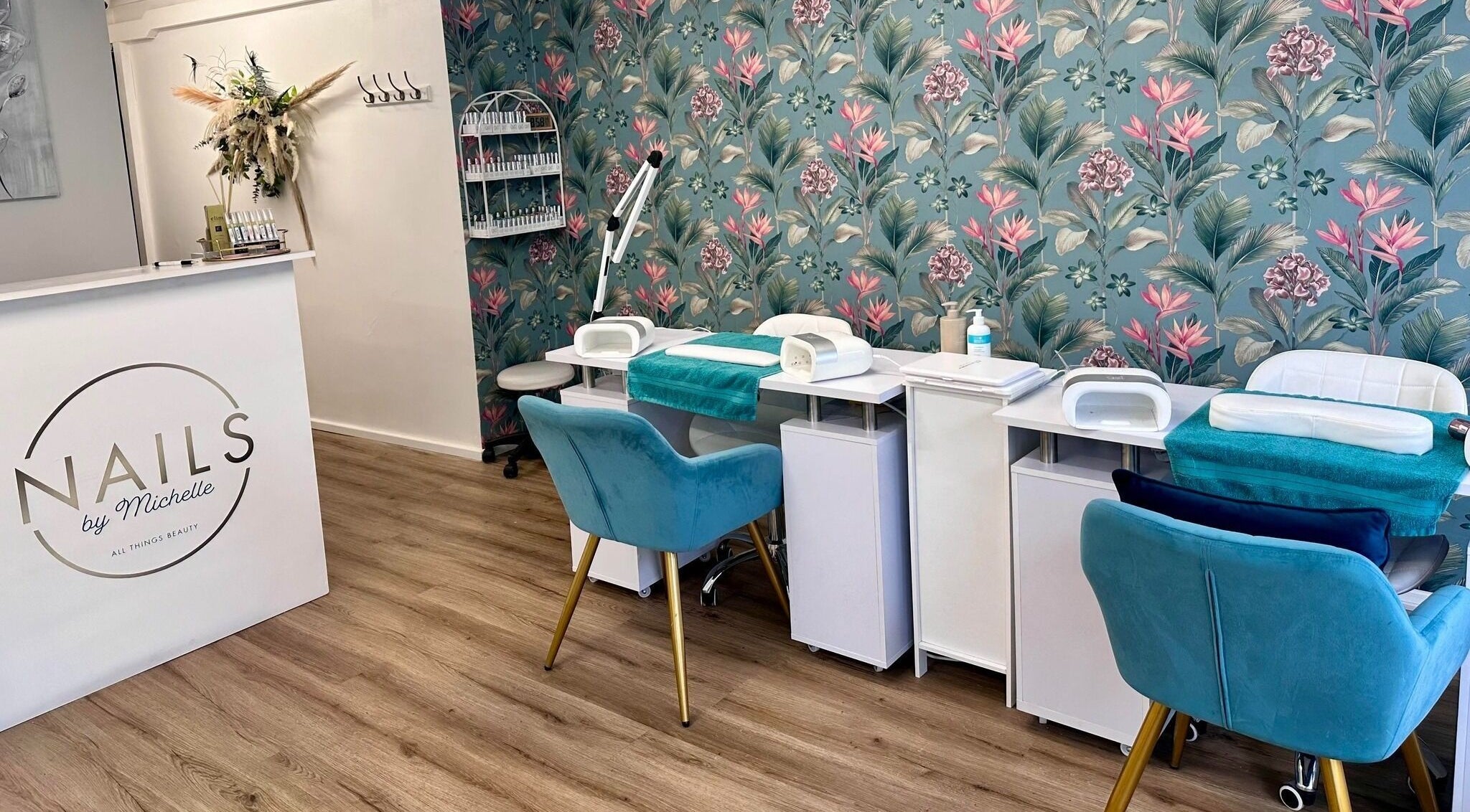Inviting nail salon setup at Nails by Michelle in Cheddar, England, GB, with floral wallpaper and teal chairs.