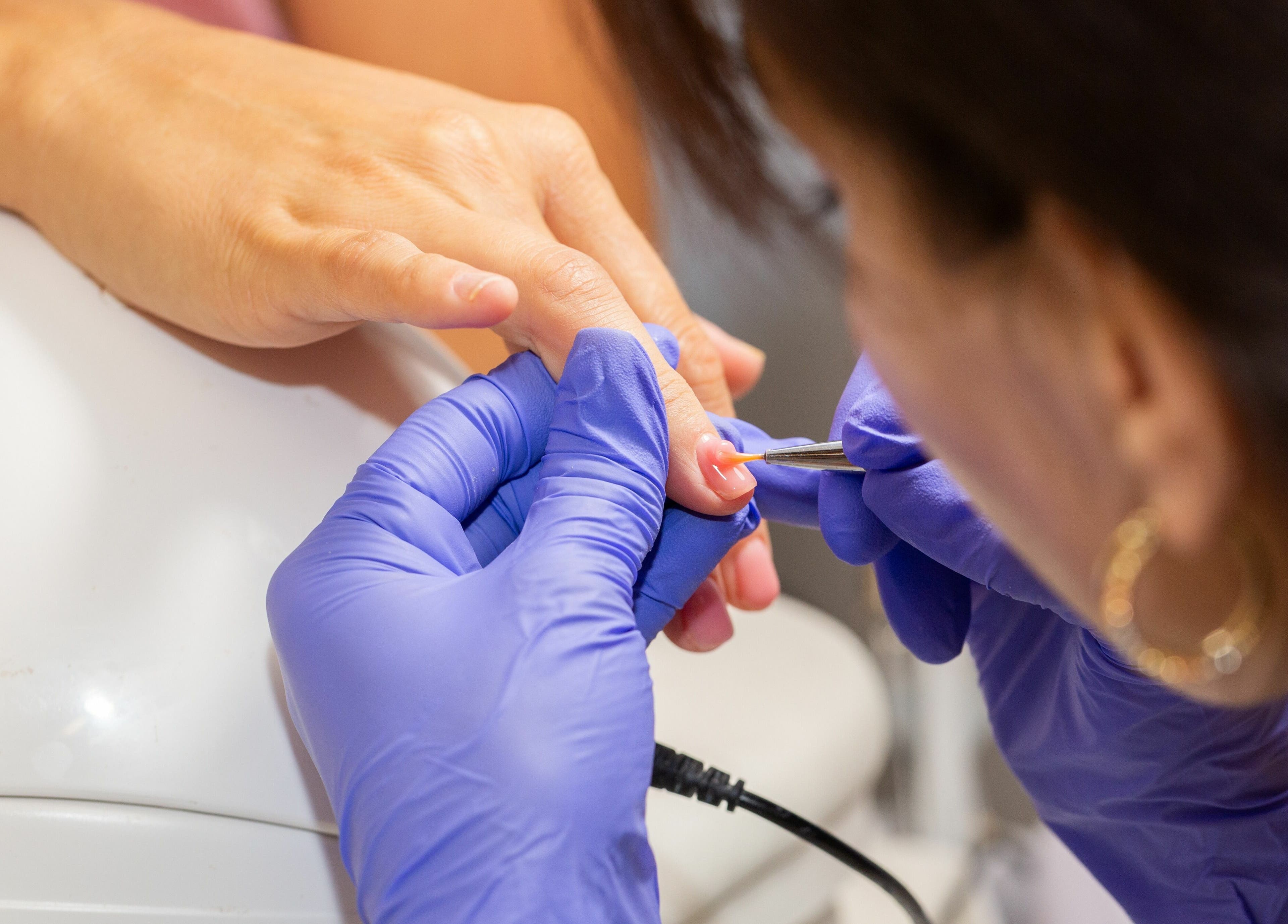 Nail technician at Zaranailsnyc in New York, US delicately shaping a client's nails with precision tools.