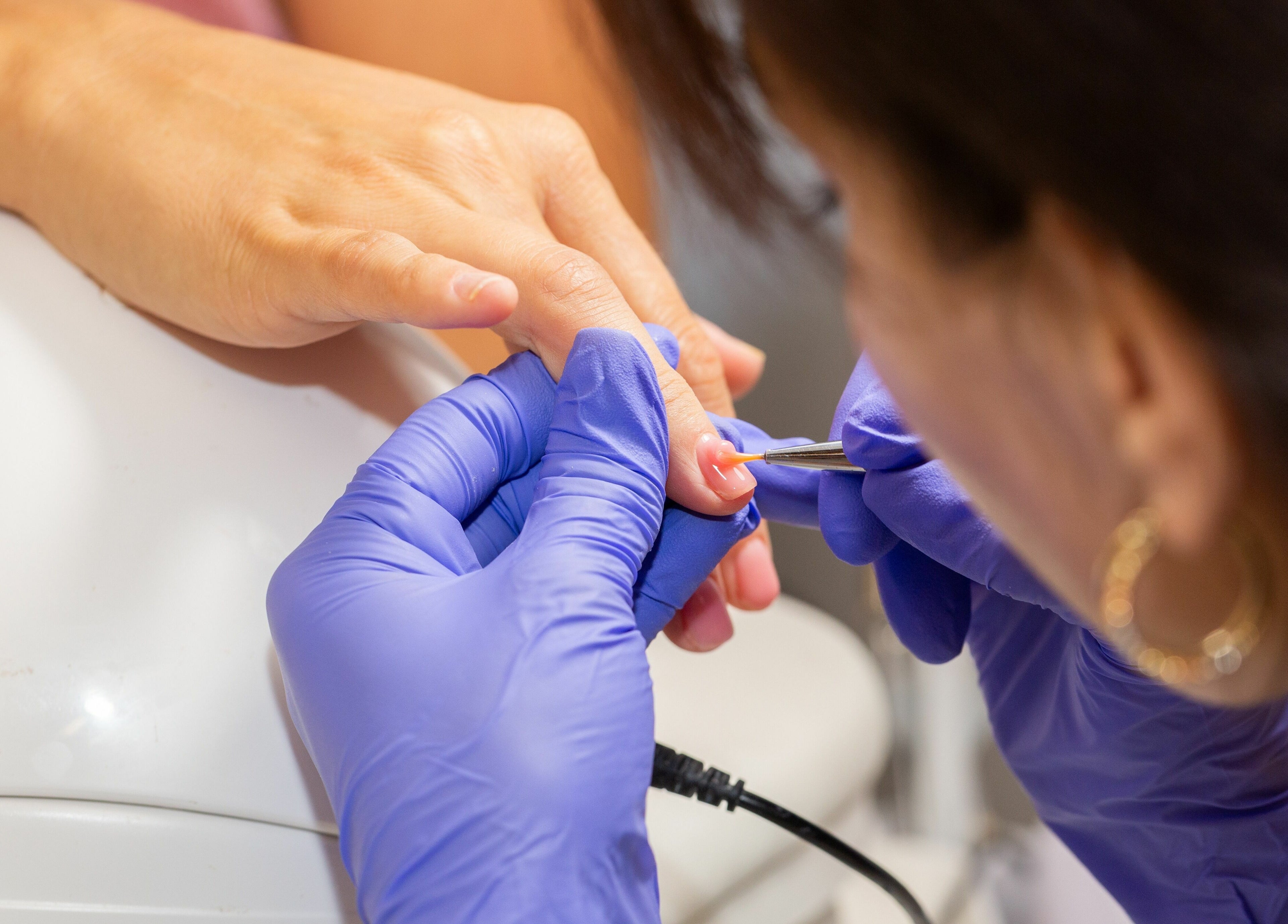 Nail technician at Zaranailsnyc in New York, US delicately shaping a client's nails with precision tools.
