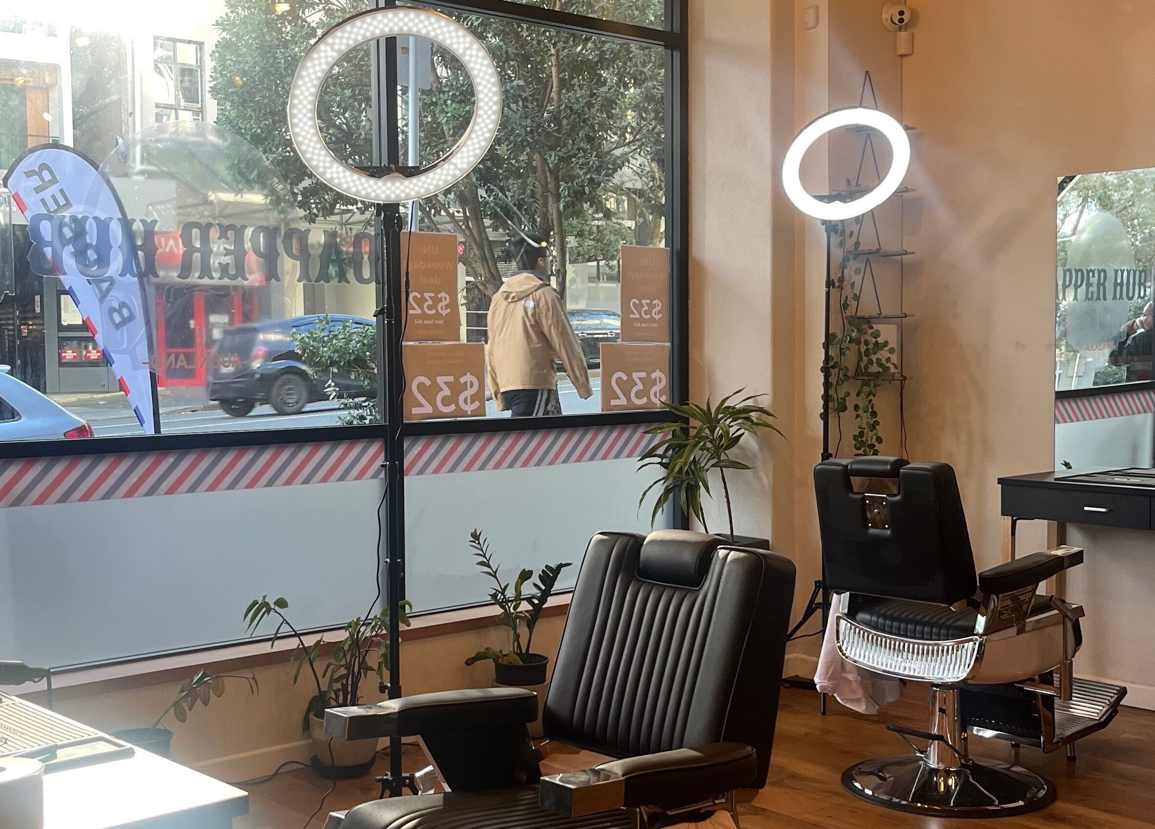 Interior of Dapper Hub Barbershop CBD, Auckland, NZ, featuring stylish chairs, mirrors, and urban street view.