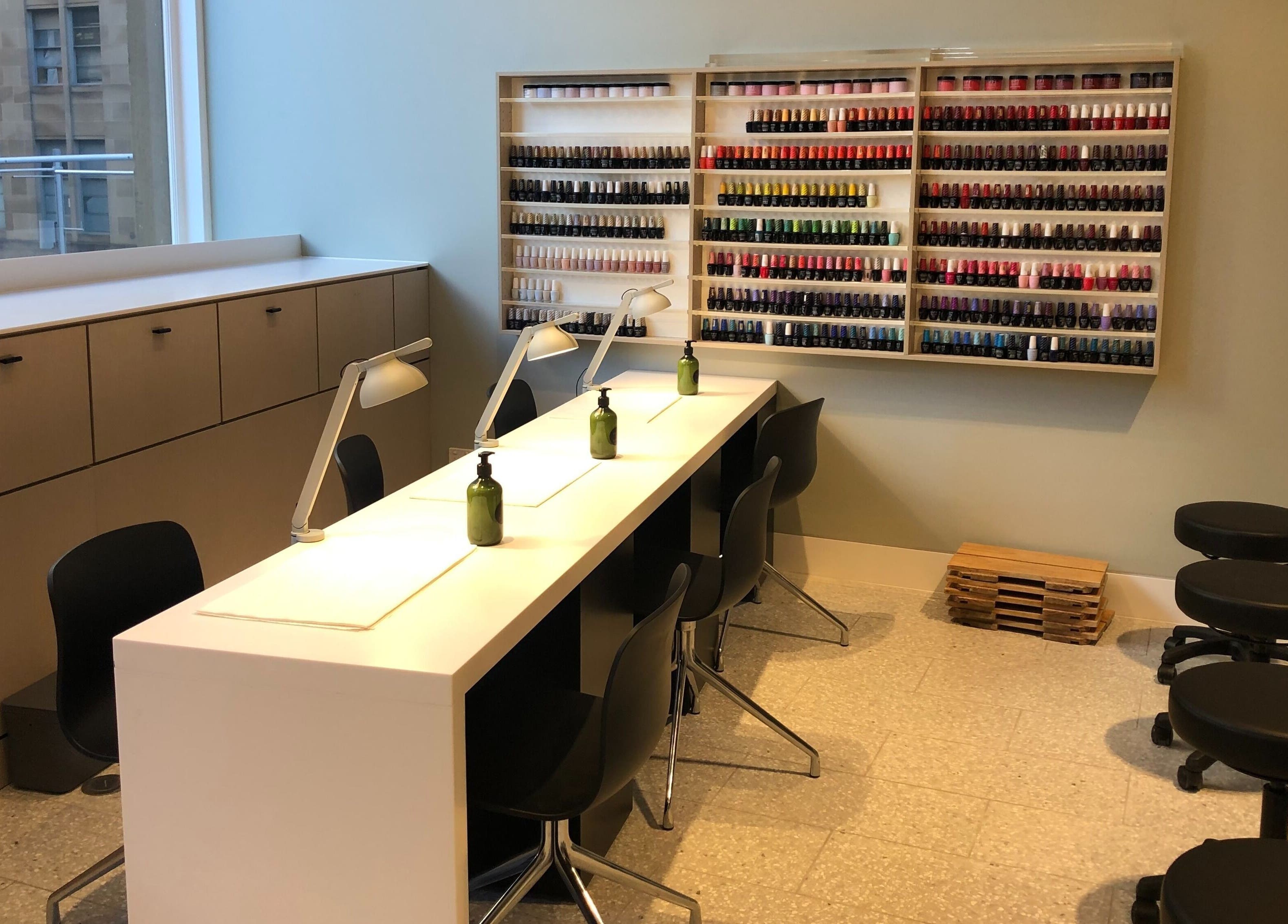 Manicure area at Beauty Bar at David Jones, Sydney, New South Wales, AU with stylish seating and colorful polish display.