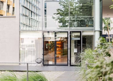 Moderní exteriér Love Your Skin, Hlavní Město Praha, CZ, s velkými skleněnými okny a zelení.