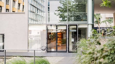 Moderní exteriér Love Your Skin, Hlavní Město Praha, CZ, s velkými skleněnými okny a zelení.