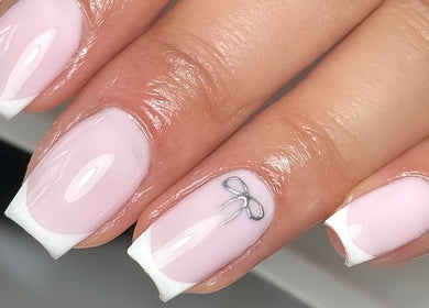 Delicate French manicure with bow design at Mais Nails, Barry, Wales, GB. Elegant and chic nail art display.