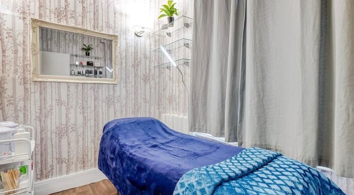 Relaxing treatment room at Joanna’s Beauty, London, England, GB, with a blue-covered bed and serene decor.