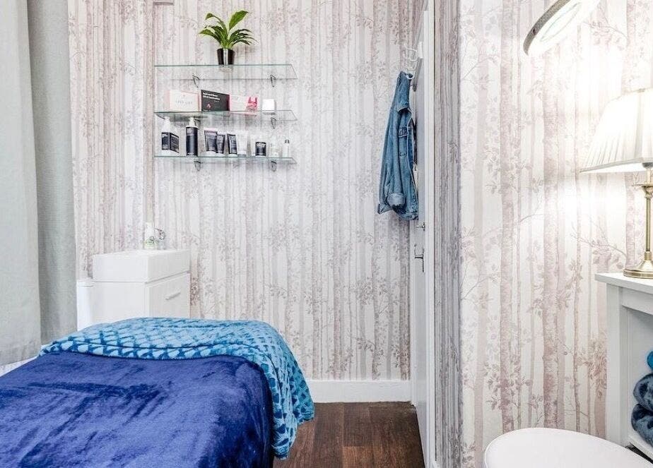 Cozy treatment room at Joanna’s Beauty, London, England, GB, featuring plush blue bedding and soft lighting.