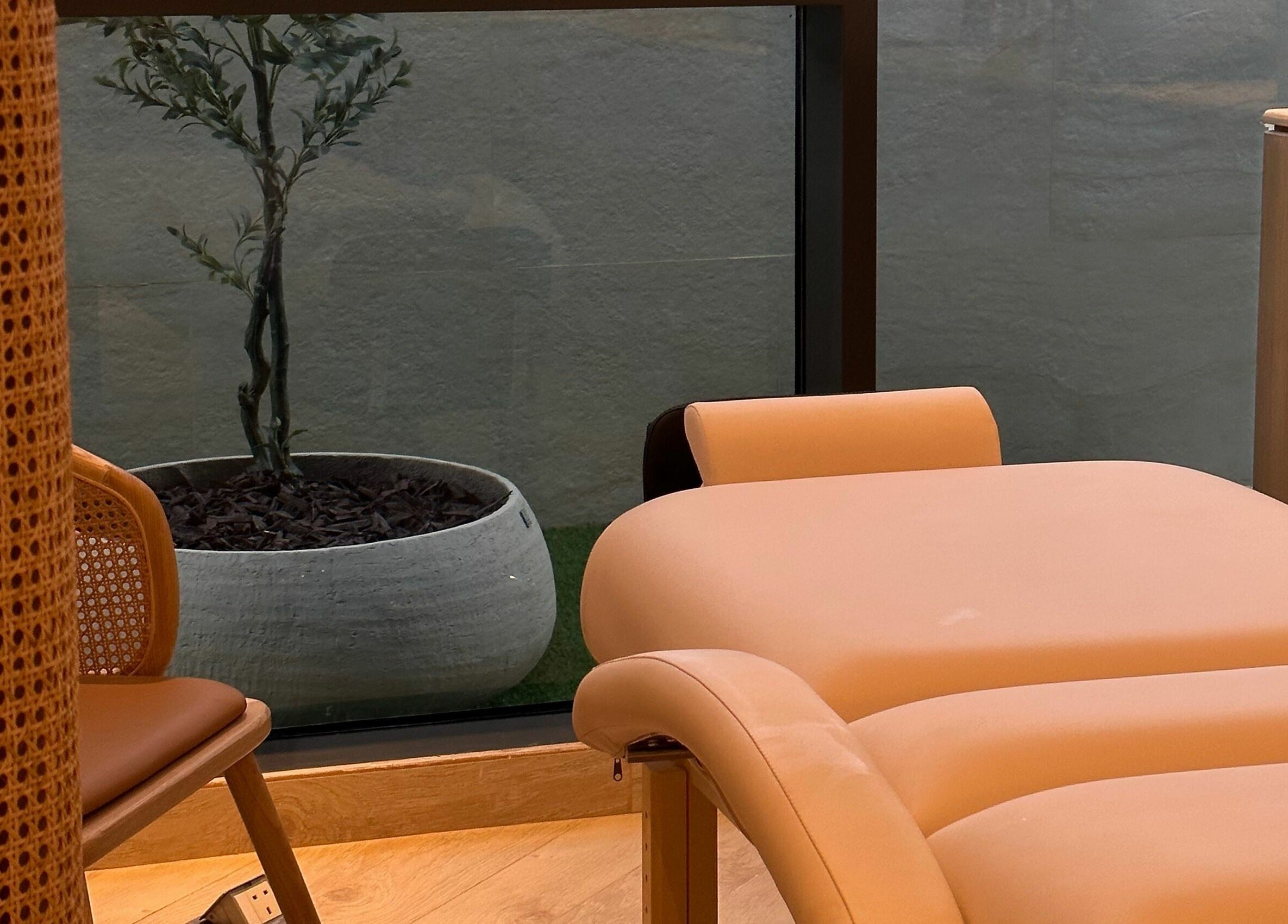 Relaxing massage table at Etc Boutique Spa Tahlia, Riyadh, SA, beside a decorative plant and wicker chair.