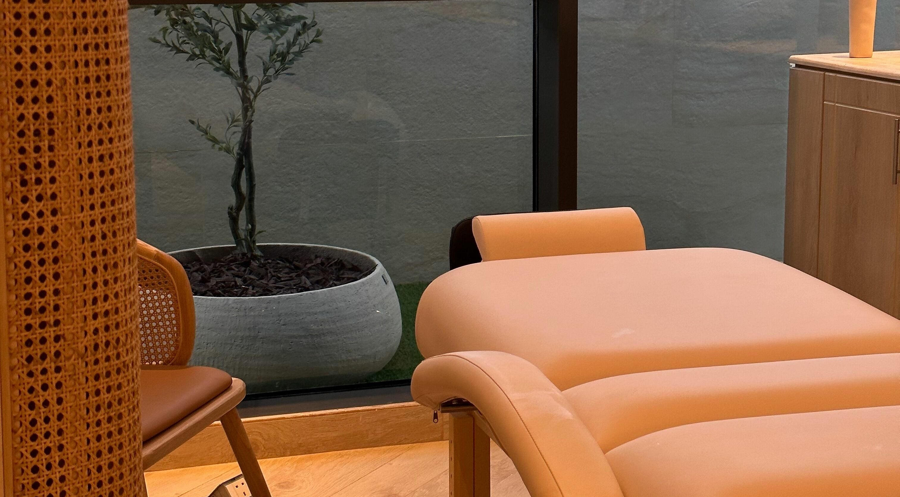 Relaxing massage table at Etc Boutique Spa Tahlia, Riyadh, SA, beside a decorative plant and wicker chair.