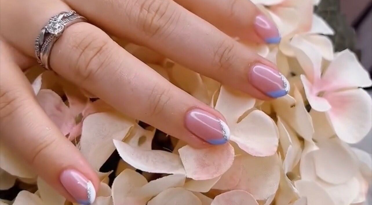 Stylish nail art at Cove Beauty Co, Poole, England, GB, showcasing blue-tipped French manicure on floral background.