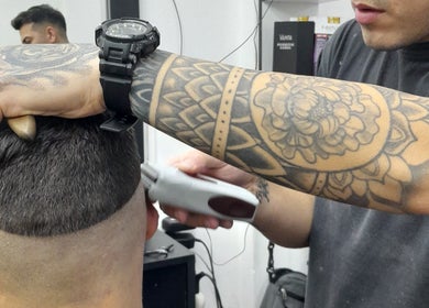 Tatuado estilista realizando corte fade en Apuro Fade, Billinghurst, Provincia De Buenos Aires, AR.
