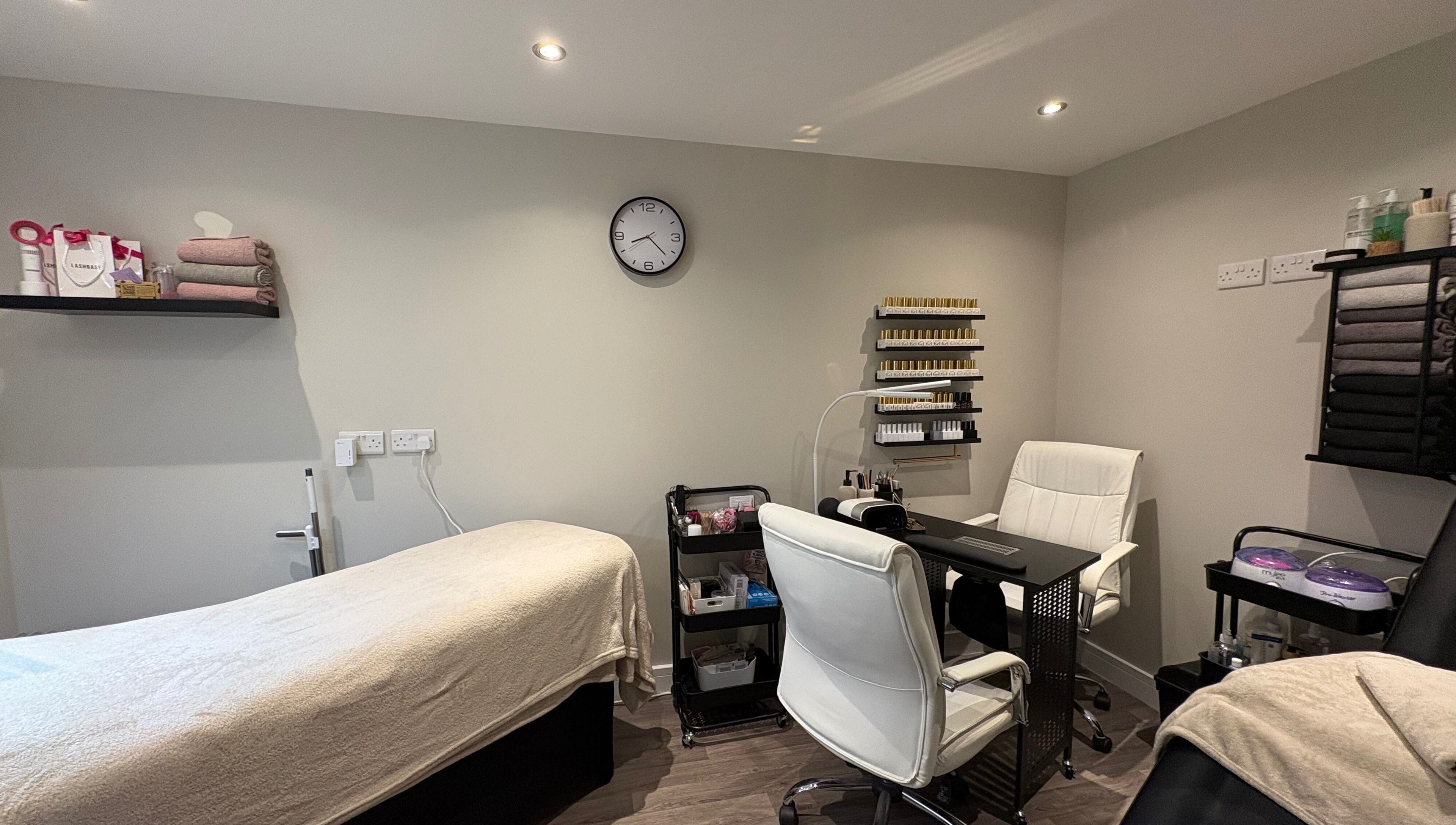 Pretty Beautiful's cozy treatment room in Waterlooville, England, GB, featuring a massage bed and nail station.