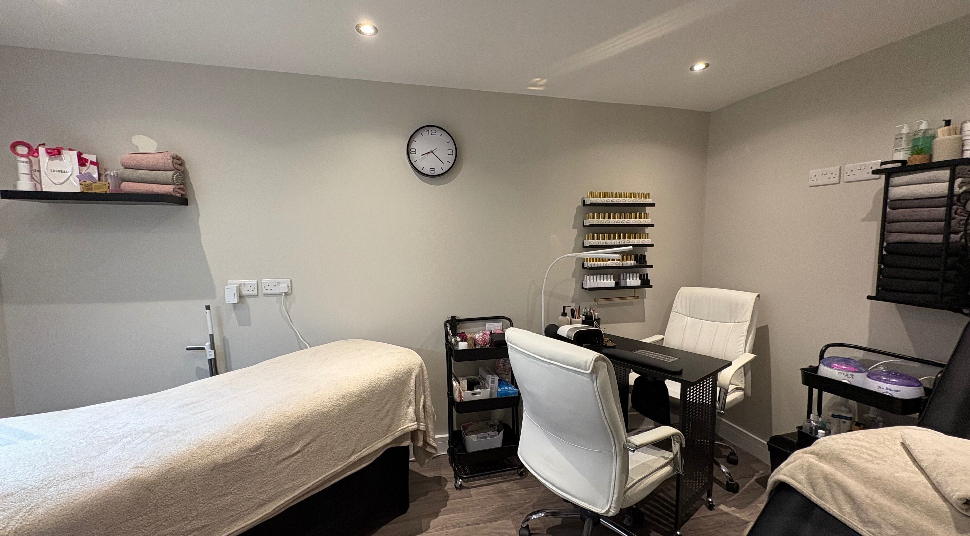 Pretty Beautiful's cozy treatment room in Waterlooville, England, GB, featuring a massage bed and nail station.