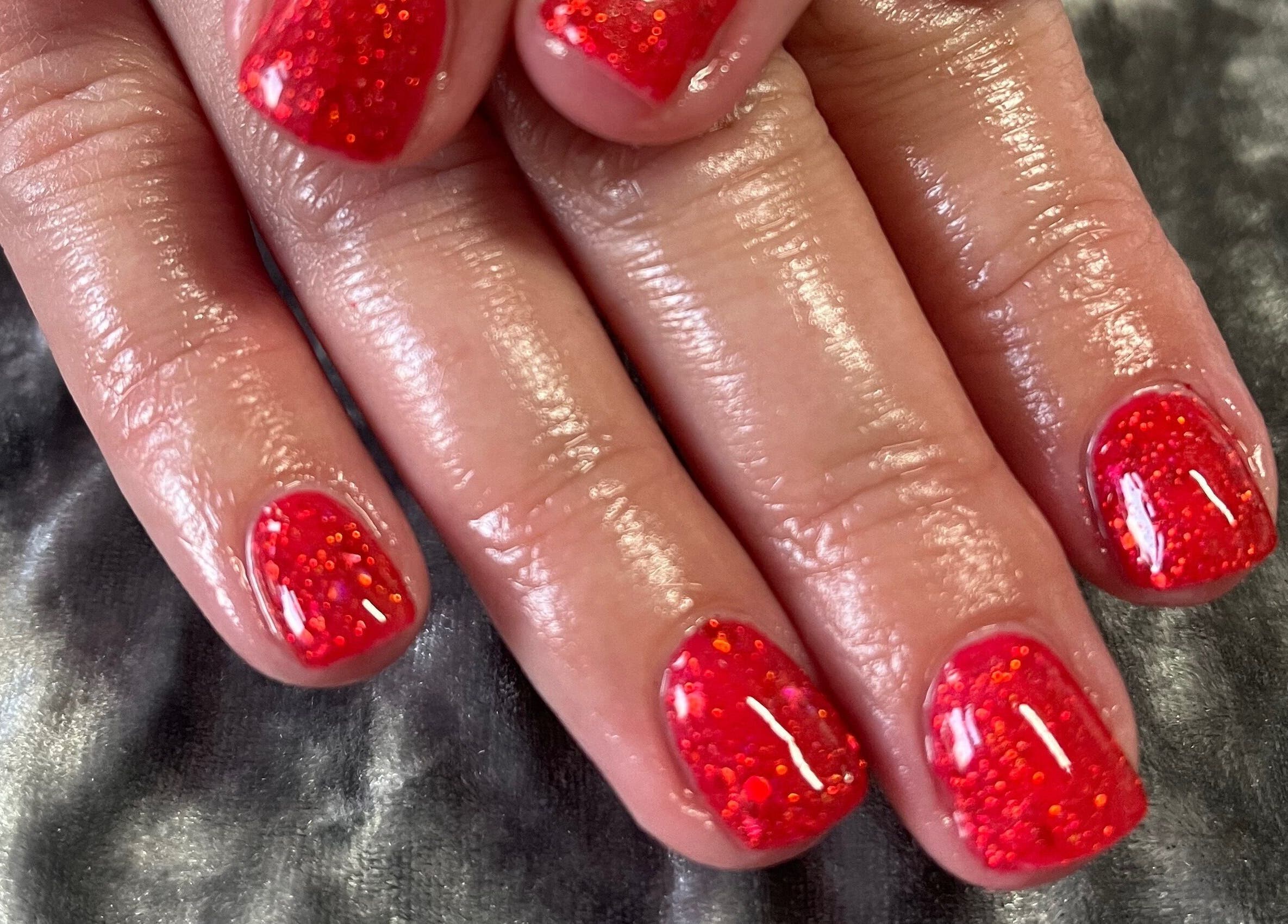Red glitter manicure at Pretty Beautiful, Waterlooville, England, GB showcasing elegant nail art.