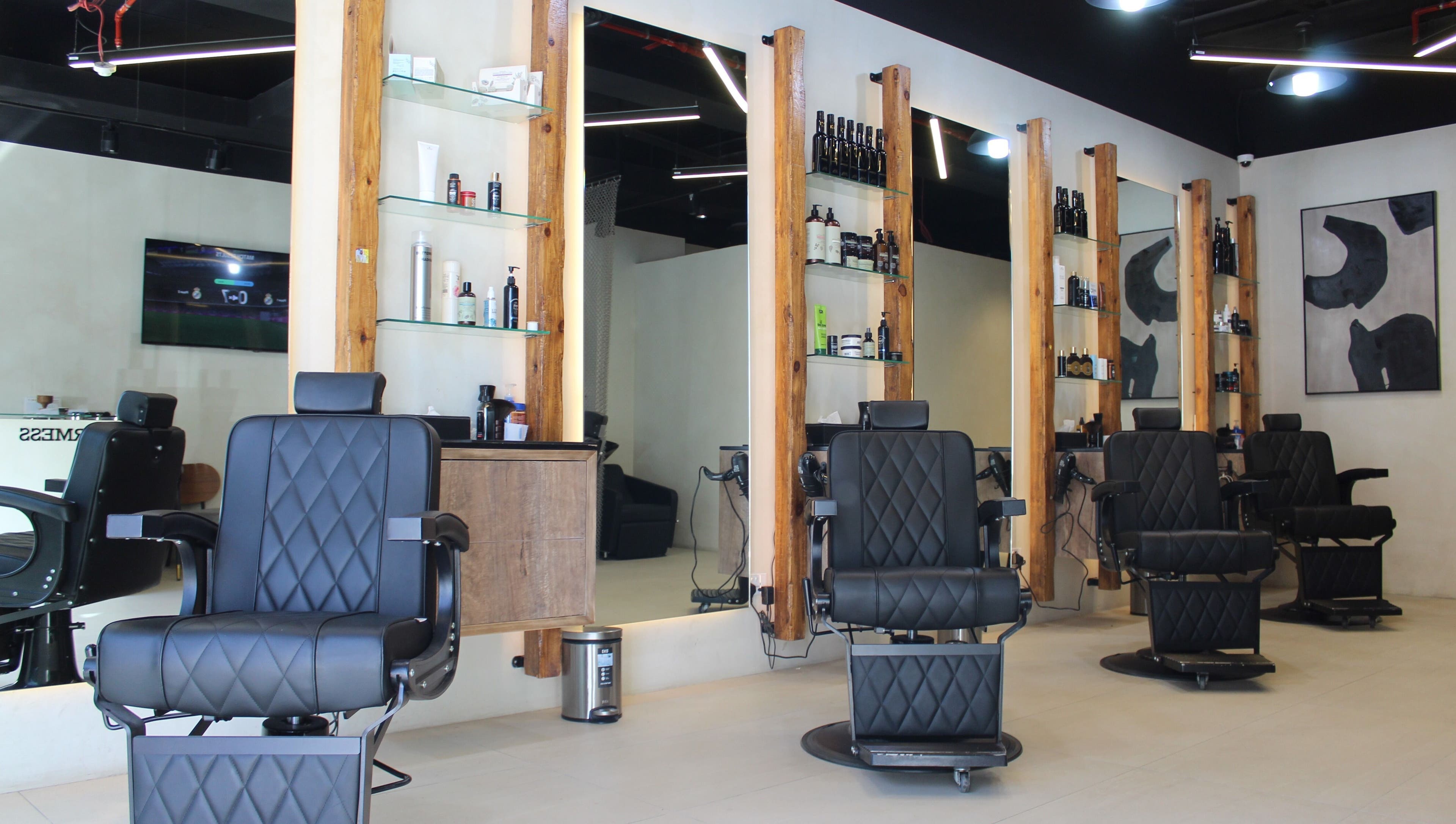 Stylish salon interior at Hairmess, Dubai, Dubai, AE with modern black chairs and wood accents.
