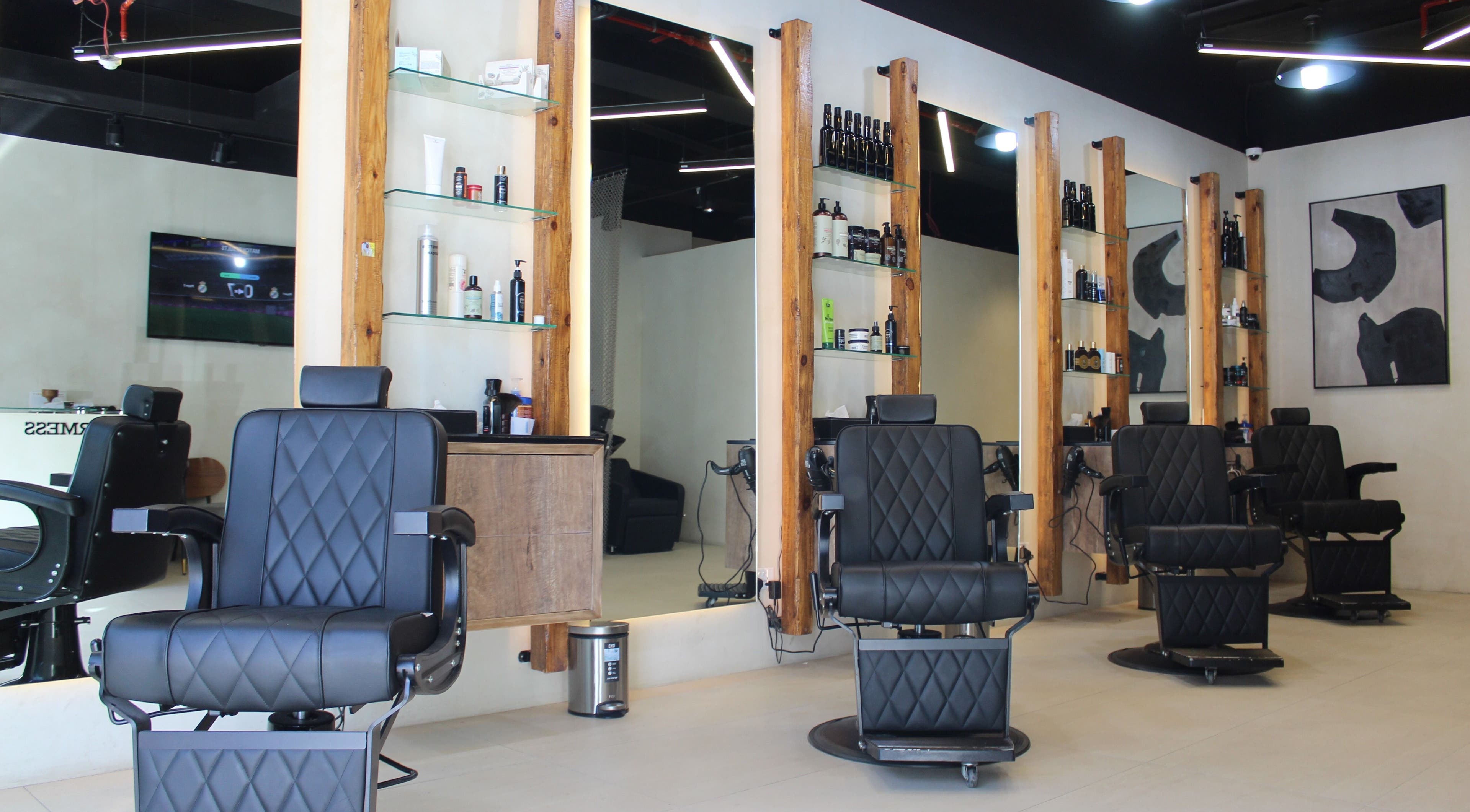 Stylish salon interior at Hairmess, Dubai, Dubai, AE with modern black chairs and wood accents.