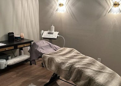 Cozy treatment room at The Body Shoppe in Darlington, Wisconsin, US with ambient lighting and comfortable bed.