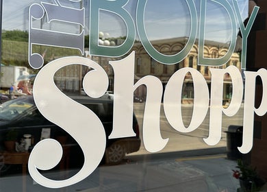 Reflective logo on The Body Shoppe window in Darlington, Wisconsin, US.