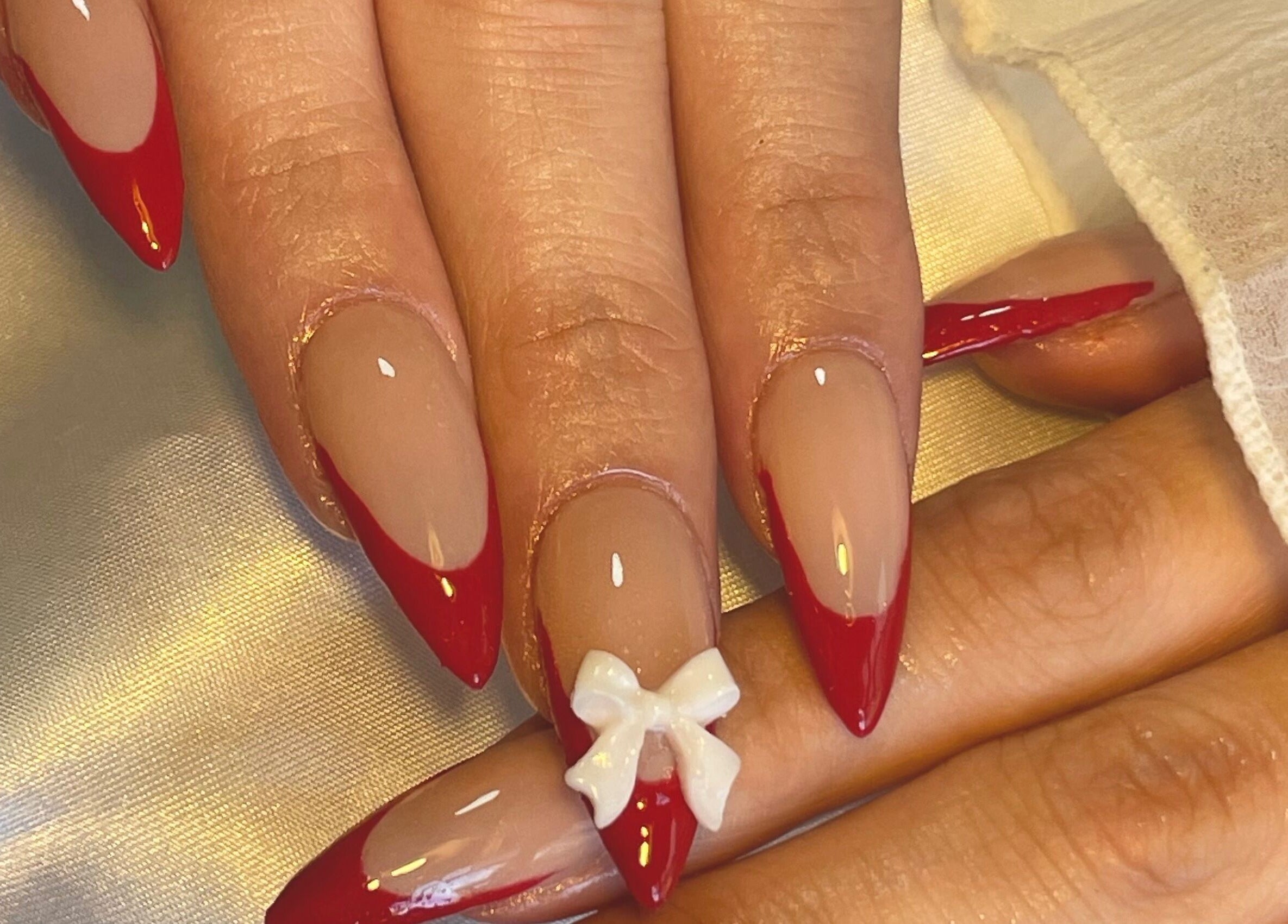 Elegant red-tipped nails with a bow at Gelled by NR in Melbourne, Victoria, AU.