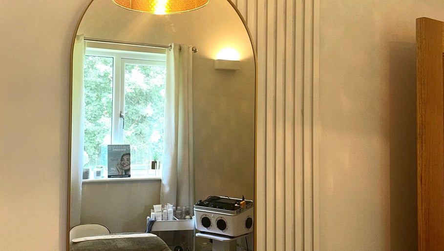 A serene treatment room at L B Aesthetics and Beauty, Ashford, England, featuring a large elegant mirror.