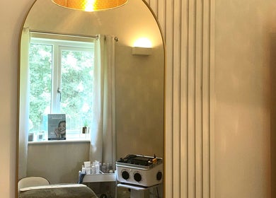 A serene treatment room at L B Aesthetics and Beauty, Ashford, England, featuring a large elegant mirror.