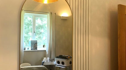 A serene treatment room at L B Aesthetics and Beauty, Ashford, England, featuring a large elegant mirror.