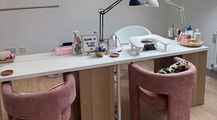 Elegant beauty studio setup at By Lilly Studio, Wilmslow, England, GB with plush pink chairs and manicure tools.