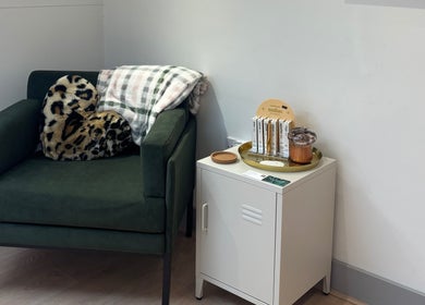 Inviting seating at By Lilly Studio, Wilmslow, England, GB, featuring a plush green chair with a leopard pillow.