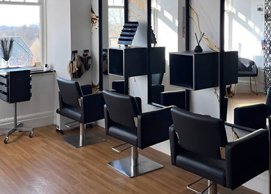 Modern salon interior at Hair by Keri Muir in Larbert, Scotland, GB featuring sleek black chairs and styling stations.