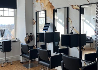 Modern salon interior at Hair by Keri Muir, Larbert, Scotland, GB with sleek black chairs and elegant mirrors.