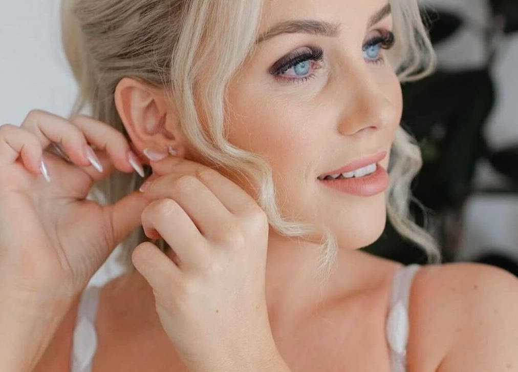 Woman adjusting earring at Lash Empire Eyelash Extensions in Razorback, New South Wales, AU.