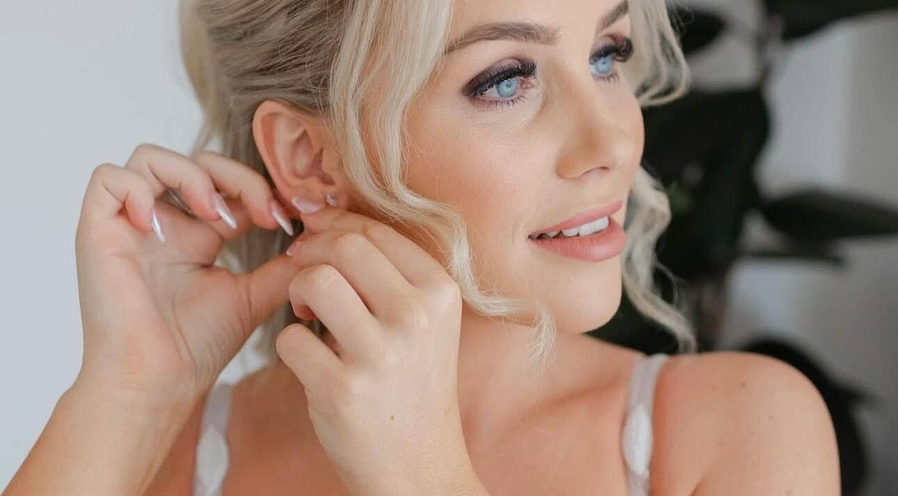 Woman adjusting earring at Lash Empire Eyelash Extensions in Razorback, New South Wales, AU.
