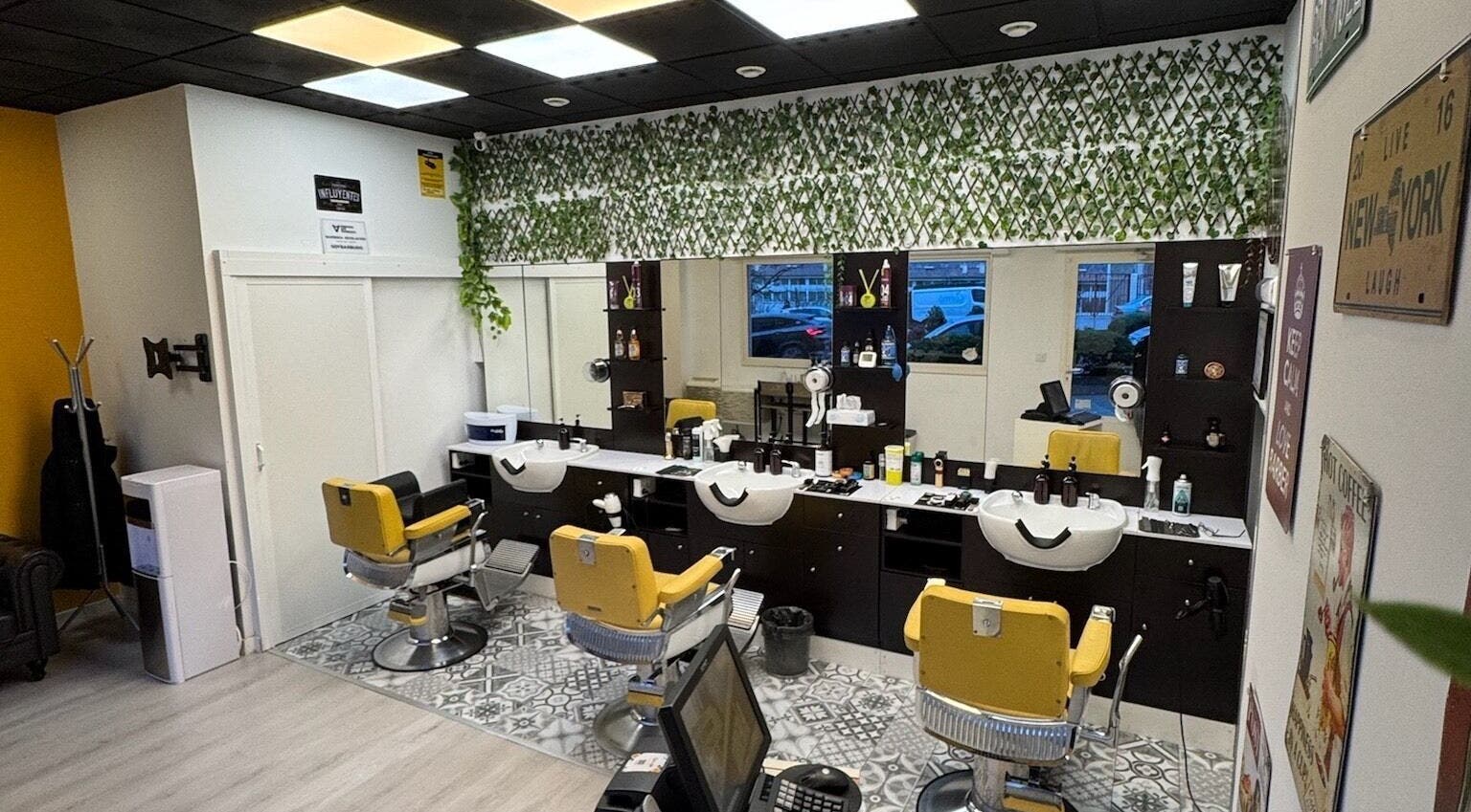 Interior de Barberia Oro Negro en Vigo, ES, con sillas amarillas y decoración verde en el salón.