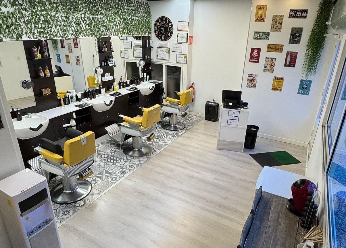 Interior moderno de Barberia Oro Negro en Vigo, ES, con sillas amarillas y decoración vintage.
