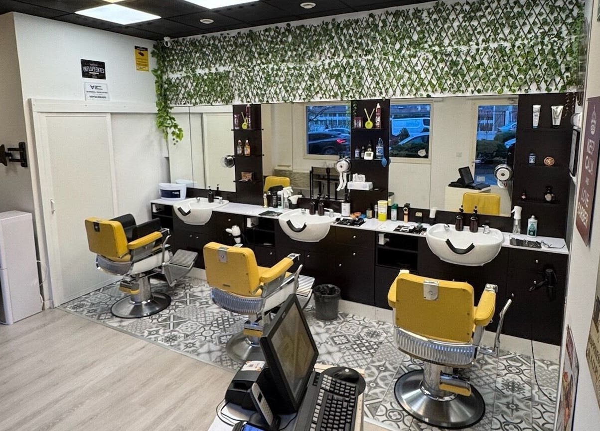 Interior moderno de Barberia Oro Negro (Martinez Garrido) en Vigo, ES, con sillas amarillas y decoración de plantas.