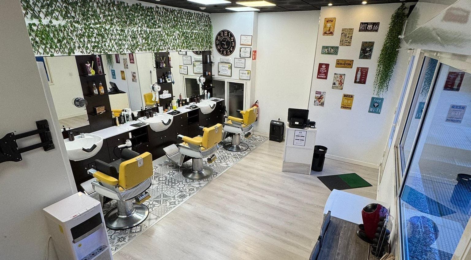 Interior moderno de Barberia Oro Negro, Vigo ES, con sillas amarillas y decoración vibrante.